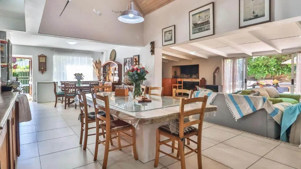 Open-plan living and dining area with a glass-top table, vaulted ceiling and sliding doors onto the patio