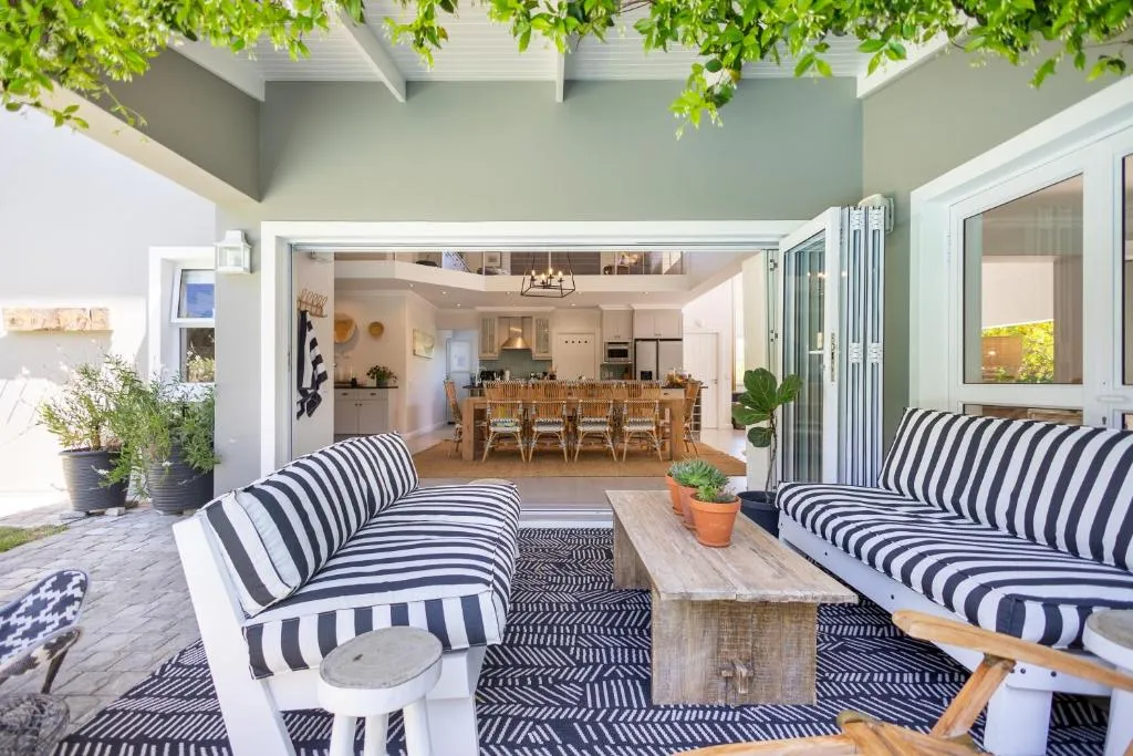 Covered patio with striped sofas opening onto the kitchen and dining area, with a mezzanine above