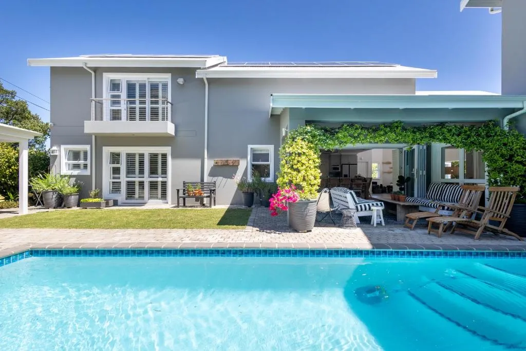 Double-storey house exterior with shuttered windows, solar panels and a poolside patio