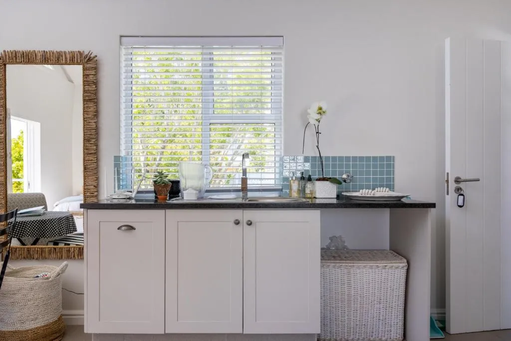Kitchenette counter with a sink beneath a window and a large woven-frame mirror