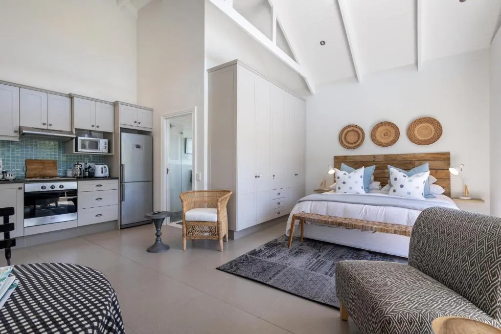 Open-plan loft studio combining a galley kitchen with a king bed under a high raked ceiling