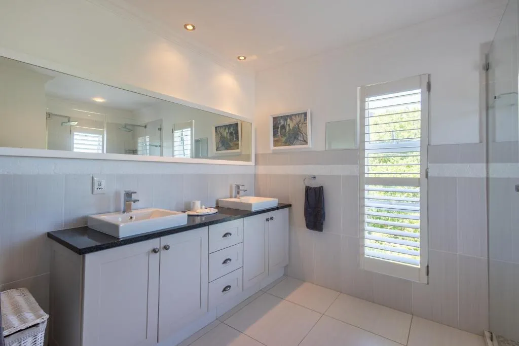 Bathroom with a double vanity, black countertop and a separate glass shower
