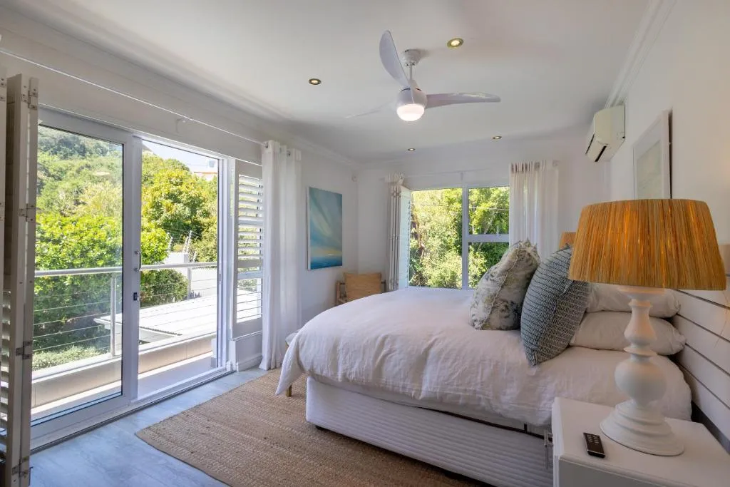 Bedroom with glass doors onto a balcony, ceiling fan and a wall-mounted air conditioner