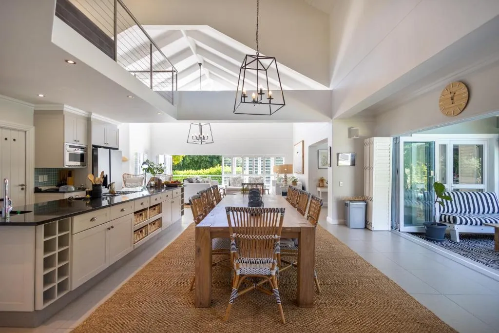 Open-plan kitchen and dining room under a vaulted skylight, with a long wood table for eight