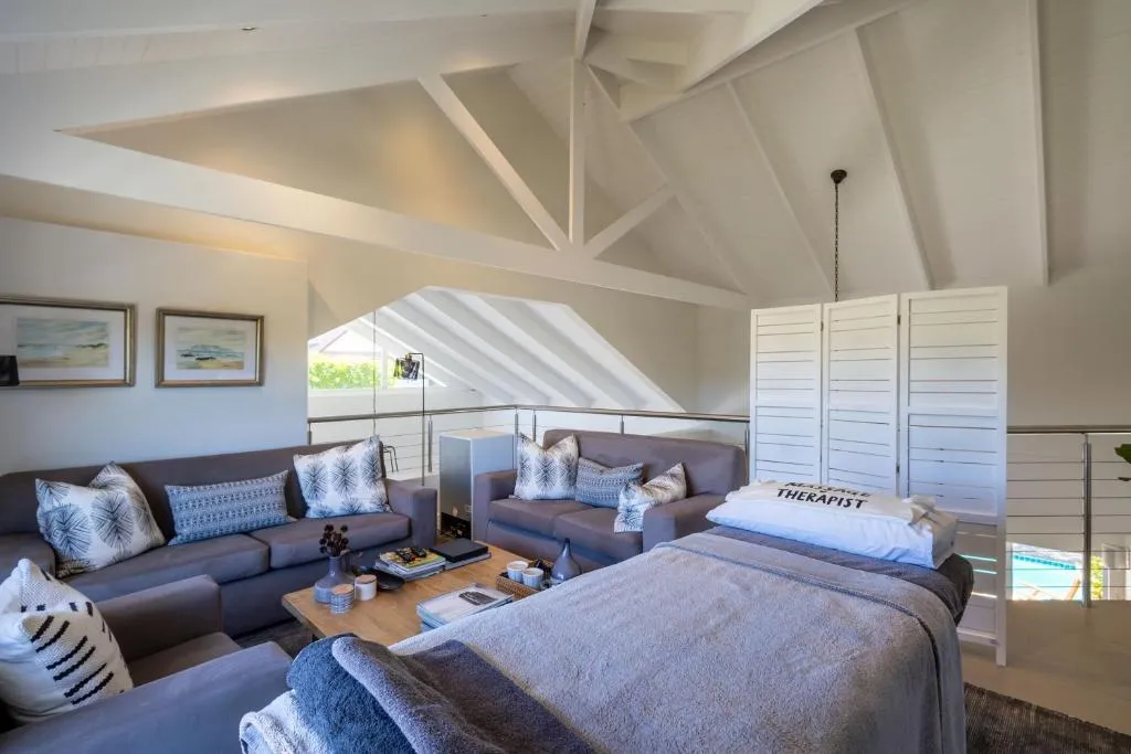 Loft lounge with sofas, a draped treatment table and a glimpse of the pool below