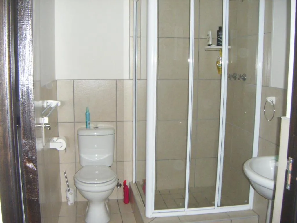 Bathroom with a glass-enclosed shower stall beside a toilet and pedestal basin