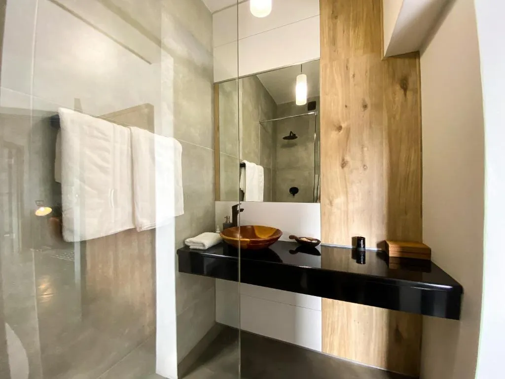 En-suite bathroom with a floating black vanity, wood-slab wall, and glass shower screen