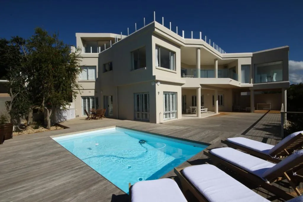 Three-storey house exterior with a private pool, wooden deck and glass balustrades
