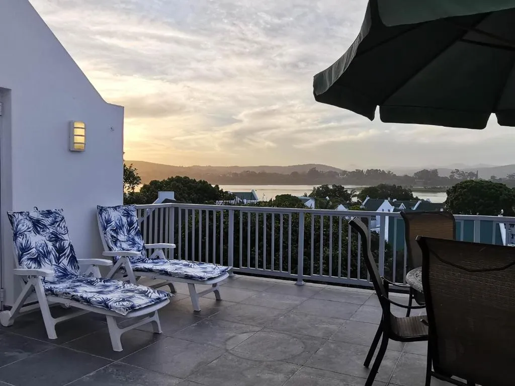 Rooftop terrace with loungers and a dining set overlooking the Keurbooms lagoon at sunset
