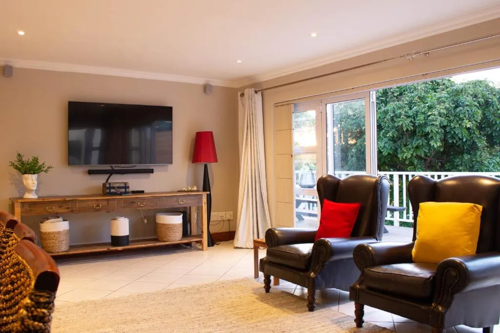 Second lounge with leather wingback chairs and sliding doors onto a tree-lined balcony