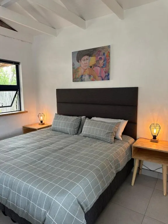 Bedroom nook with a checkered duvet, dark upholstered headboard and bedside lamps