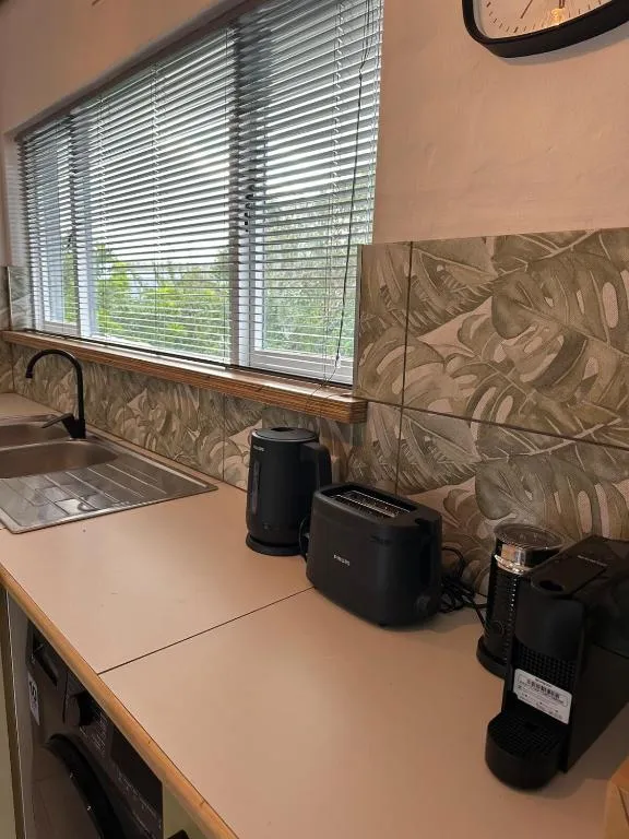 Kitchenette counter with kettle, toaster, coffee machine and a window over the sink