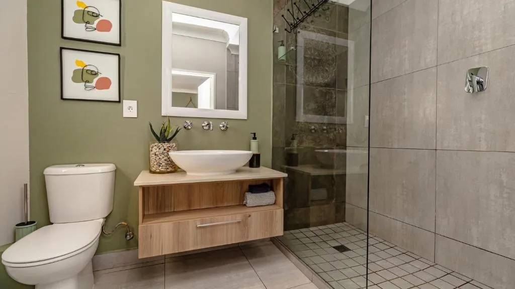 Bathroom with a vessel basin, walk-in glass shower and floor-to-ceiling tiling