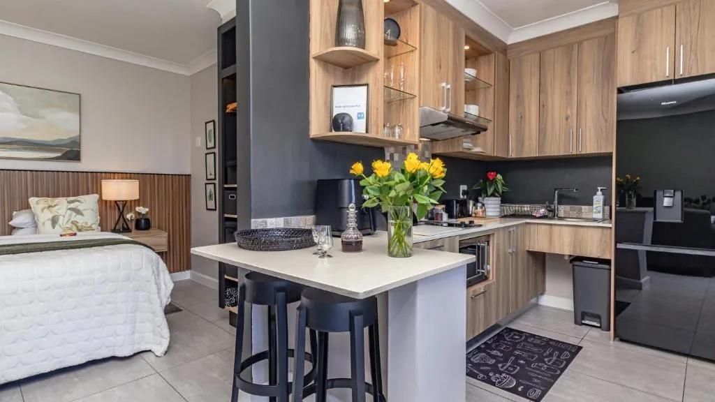 Kitchenette with wood cabinetry, a breakfast counter and stools alongside the bed