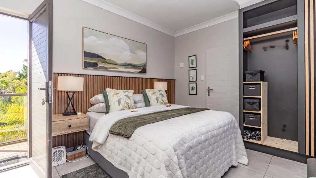 Bedroom with a wood-slat headboard and reading lamps, sliding door opening onto a private balcony