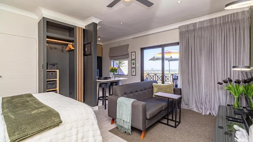 Open-plan studio lounge with a grey sofa, breakfast bar and sliding doors onto a balcony