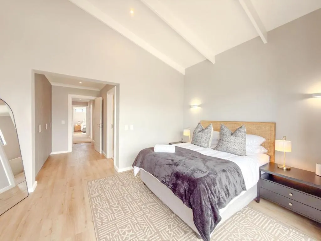 Bedroom with a vaulted ceiling, grey throw and a hallway leading to further rooms