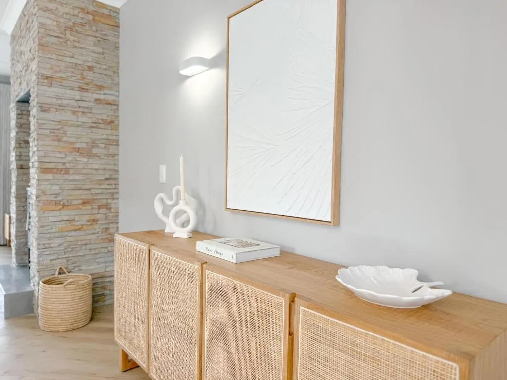 Entrance console table with a rattan cabinet, ceramic ornaments and textured wall art