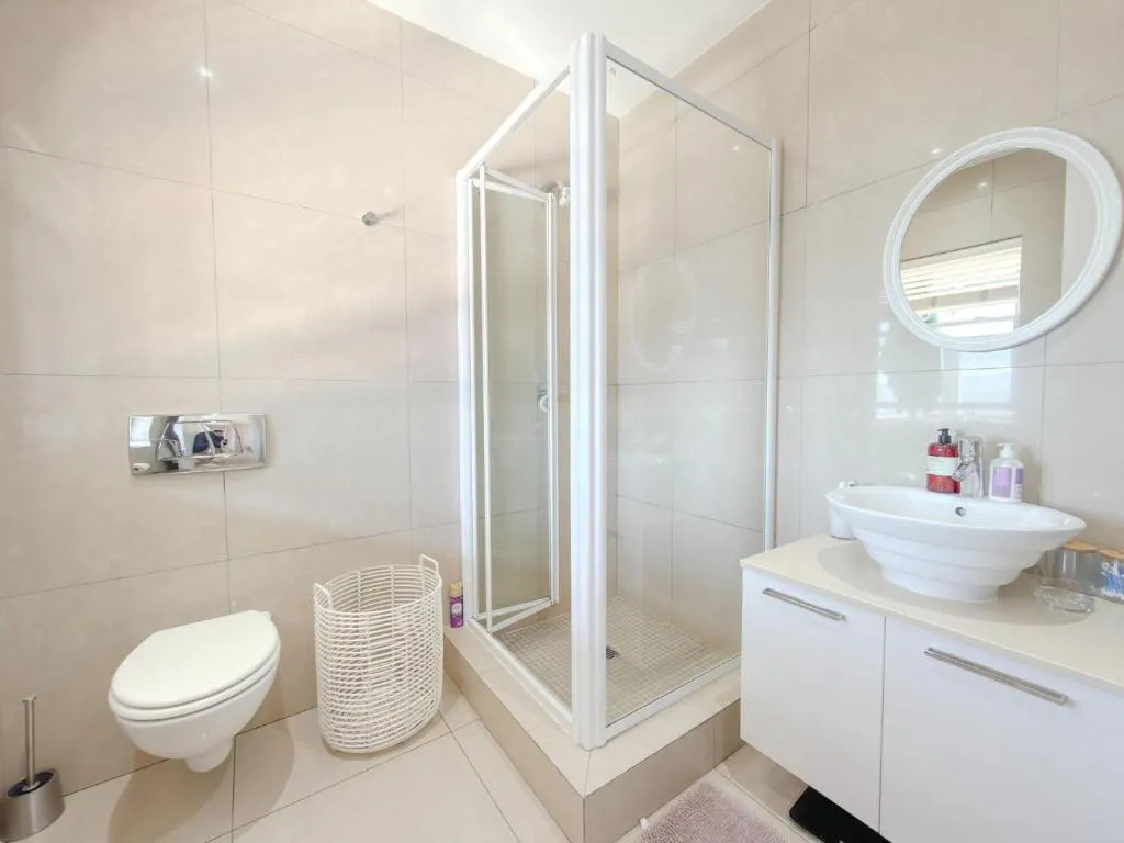 Bathroom with a corner glass shower, round mirror and oval vessel sink