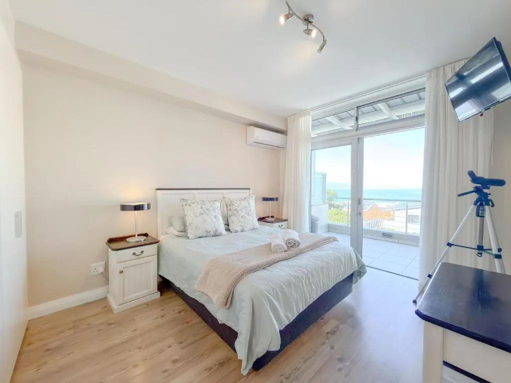 Bedroom with a sliding door onto a balcony with a sea view and air-conditioning unit