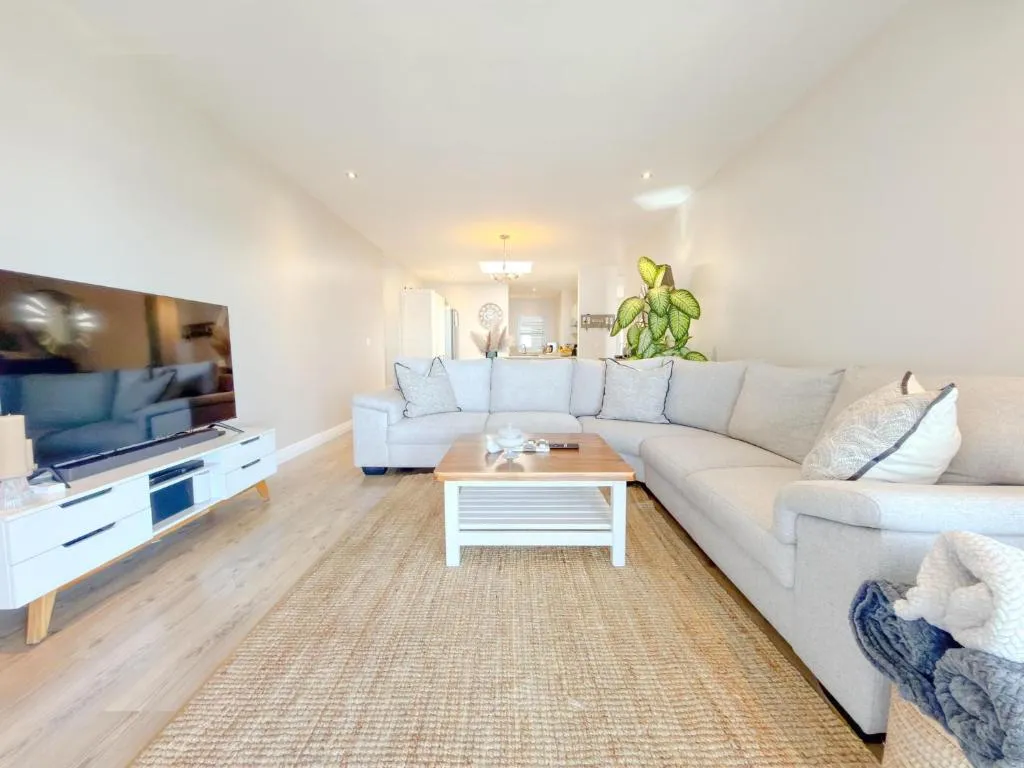 Second living area with an L-shaped sofa facing a wall-mounted TV