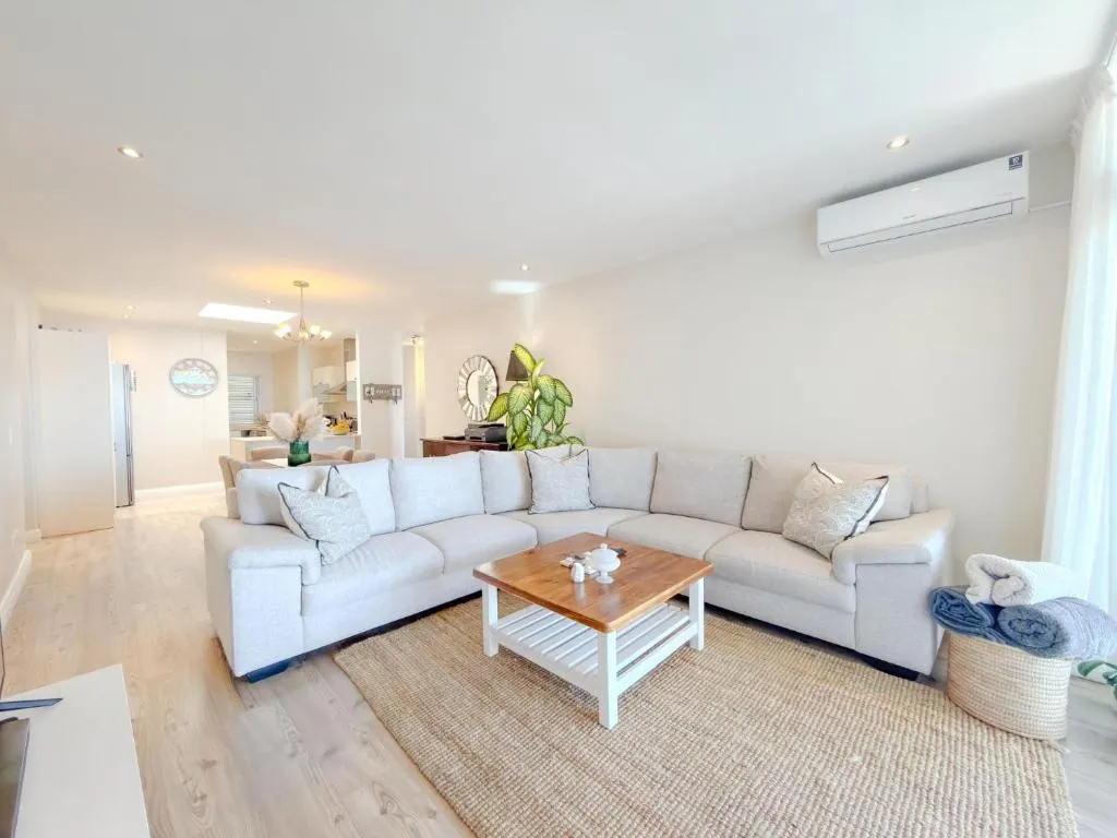 Open-plan living room with a light grey sofa and jute rug leading to the kitchen