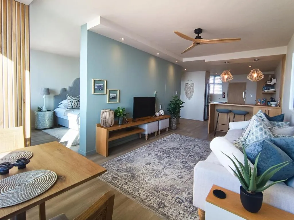Open-plan living area with a blue accent wall, TV unit and patterned rug
