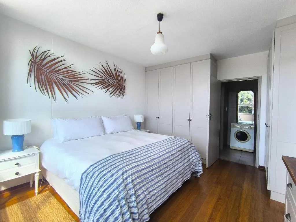 Second bedroom with palm-leaf wall art and a laundry nook with a washing machine through the door