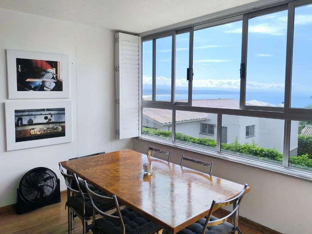 Dining table beside floor-to-ceiling windows with a clear view over rooftops to the bay