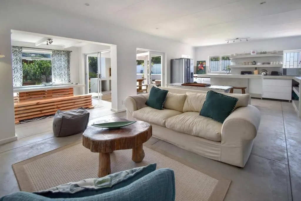 Open-plan living area with a cream sofa, driftwood coffee table and kitchen counter beyond