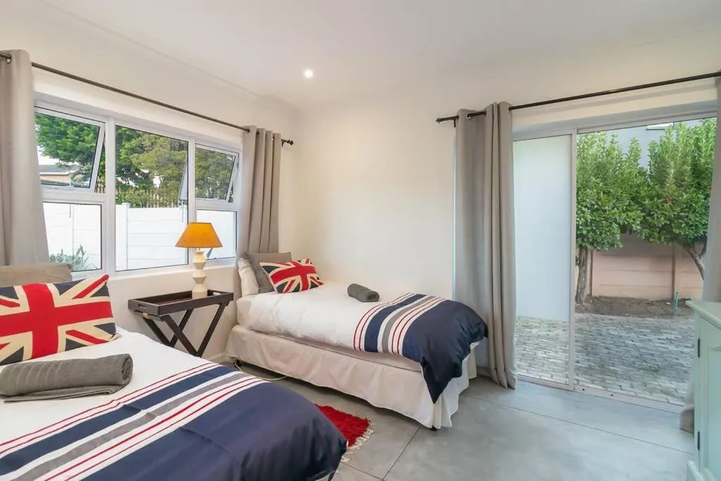 Twin bedroom with British-flag cushions and throws, sliding door onto a paved side courtyard