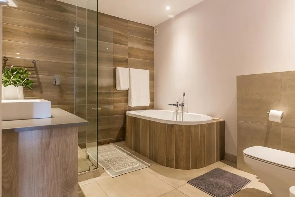 Bathroom with a wood-panelled bathtub surround, walk-in shower and freestanding vanity