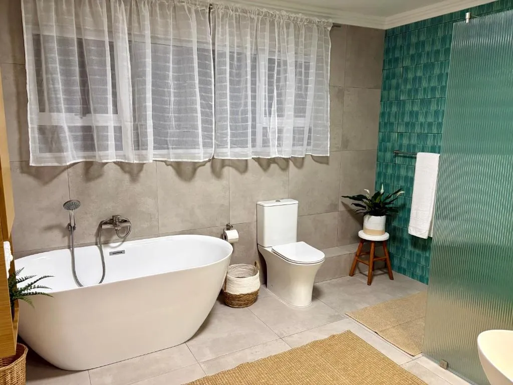 Bathroom with a freestanding tub, separate toilet, and a green-tiled walk-in shower
