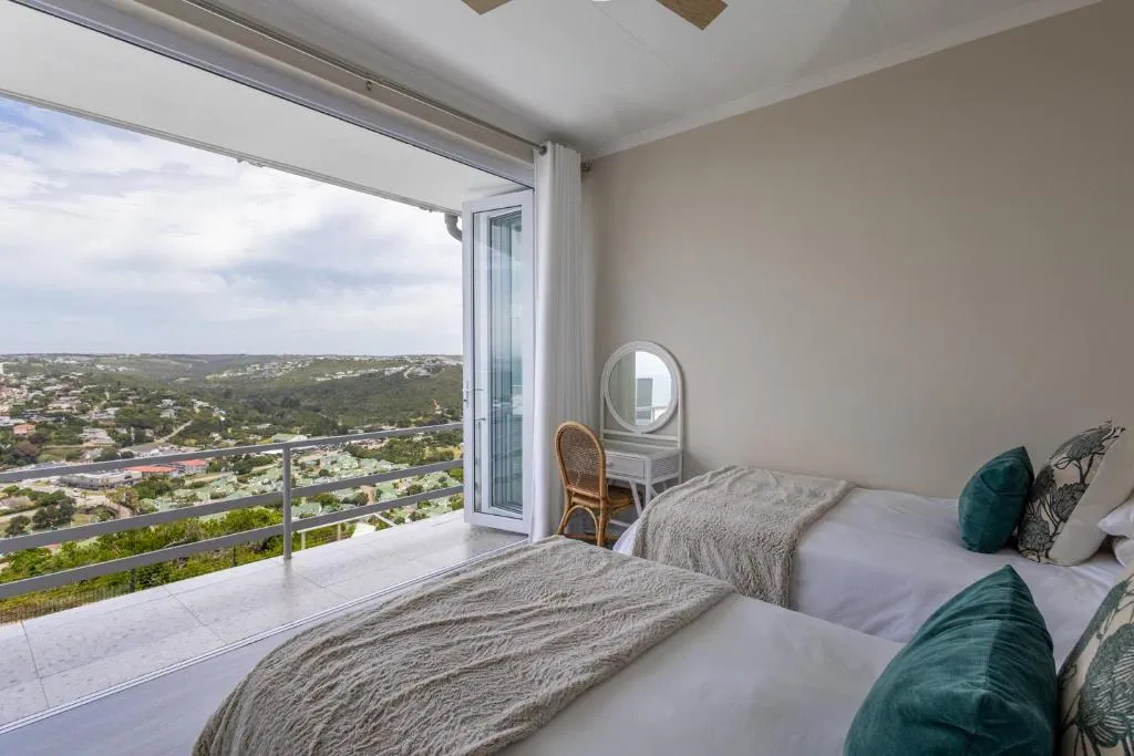 Twin bedroom opening onto a balcony with panoramic views over the hills toward the coast