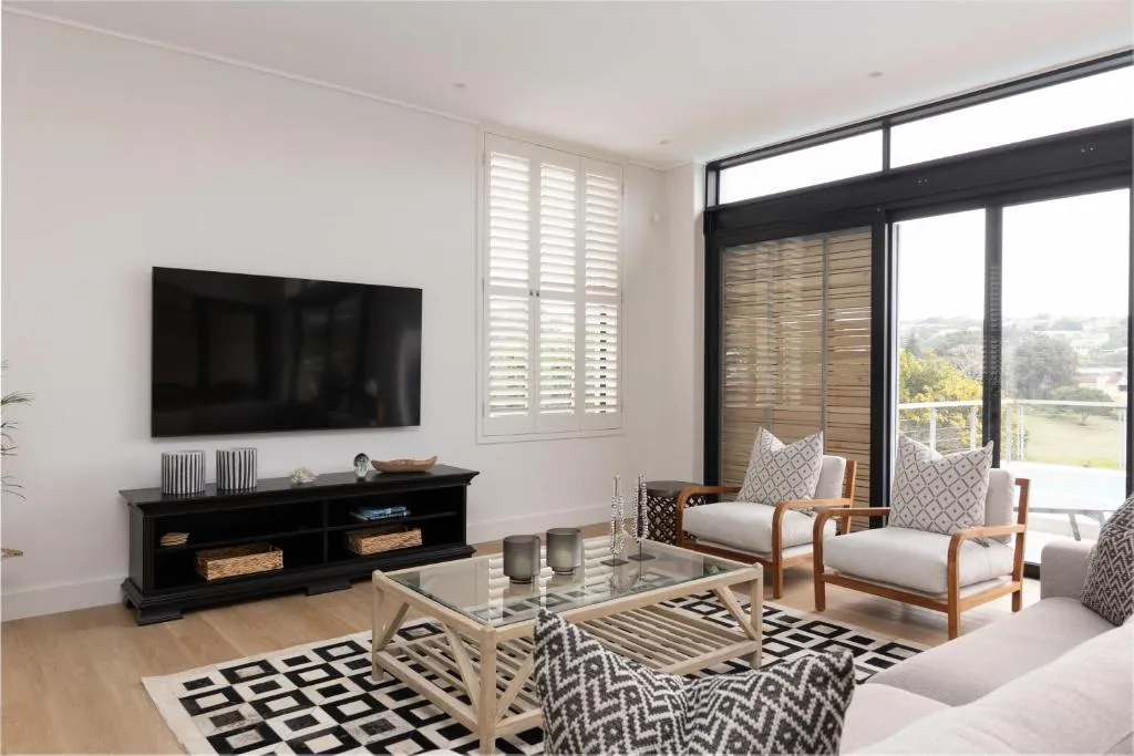 Second living space with armchairs, coffee table and sliding doors opening onto the pool terrace