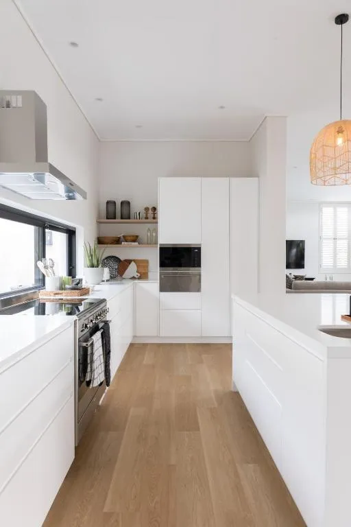 White gloss kitchen with built-in oven, extractor hood and pendant lighting over the counter