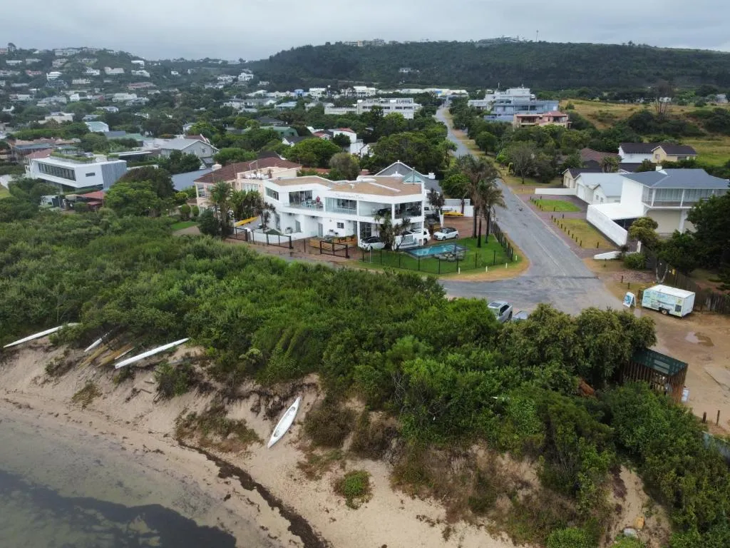 Aerial view of the property and its beachfront street, with kayaks stored on the dune below