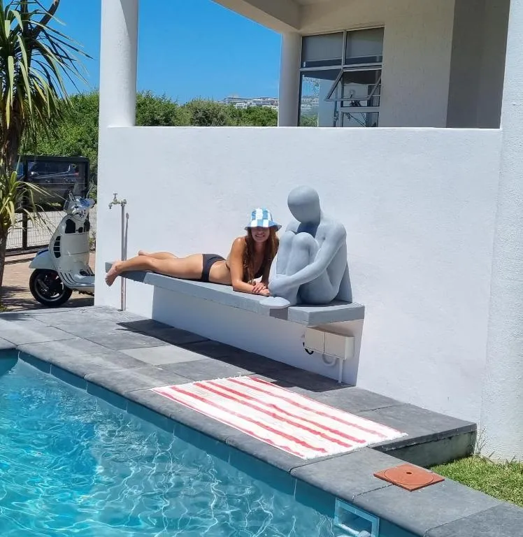 Poolside lounging area beside a sculptural bench seat and a parked scooter