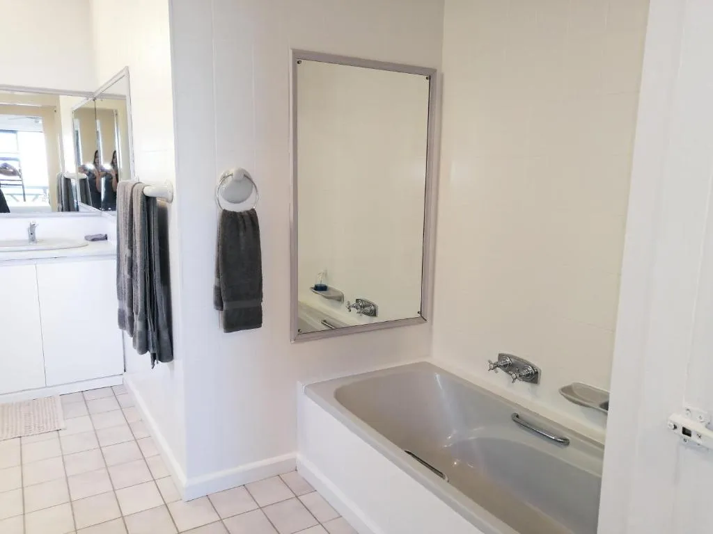 En-suite bathroom with a built-in tub, wall mirror and towel ring