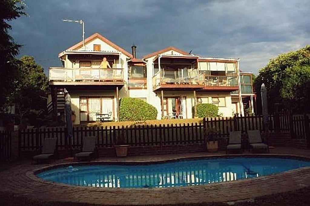 Double-storey guest house with balconies overlooking a fenced kidney-shaped pool at dusk