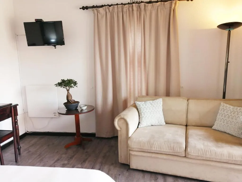 Lounge corner with a beige sofa, wall-mounted TV and floor lamp
