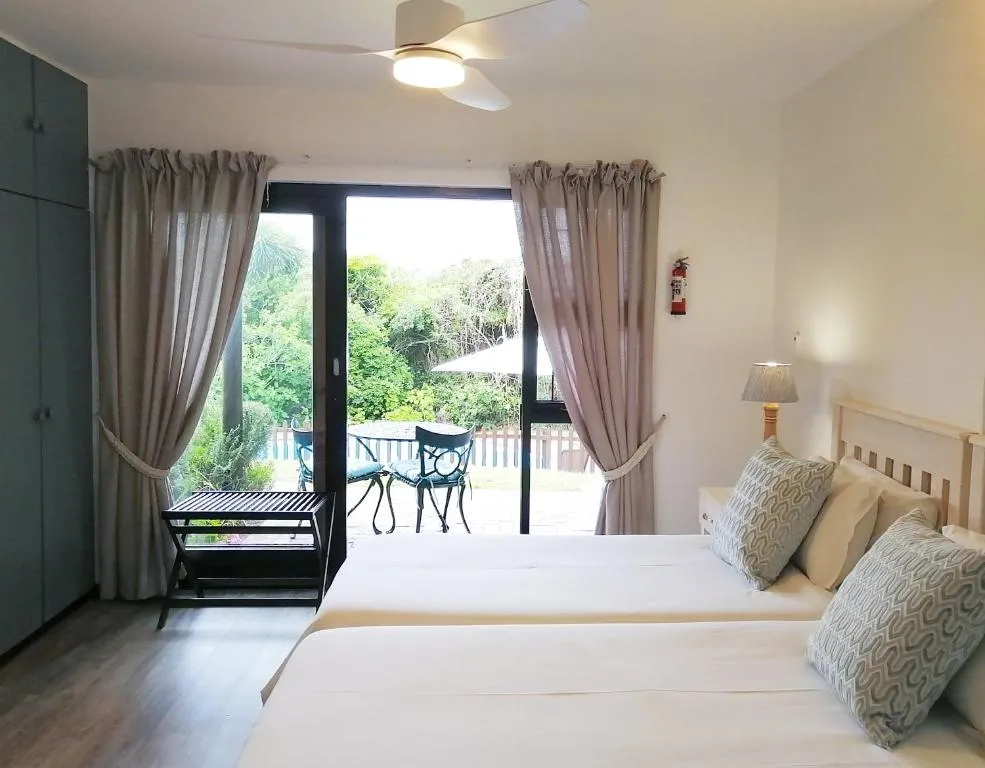 Twin beds with sliding doors opening onto a shared patio and garden