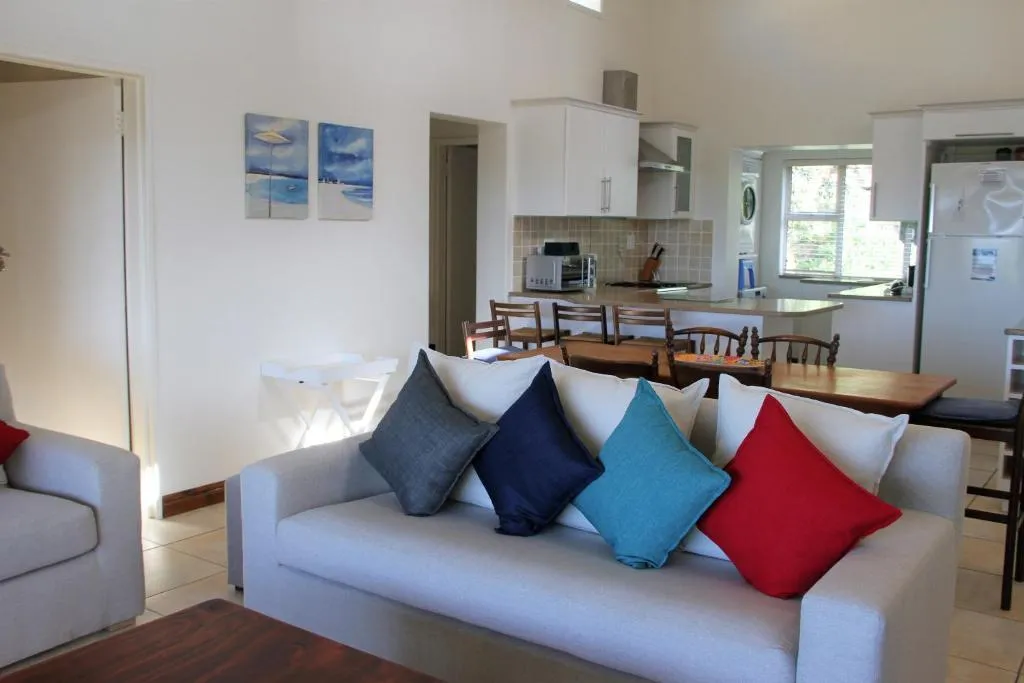 Living room with colourful scatter cushions opening onto the kitchen and dining area