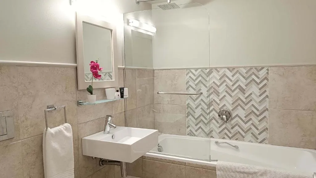 Bathroom with a chevron-tile feature wall, corner tub and vanity mirror