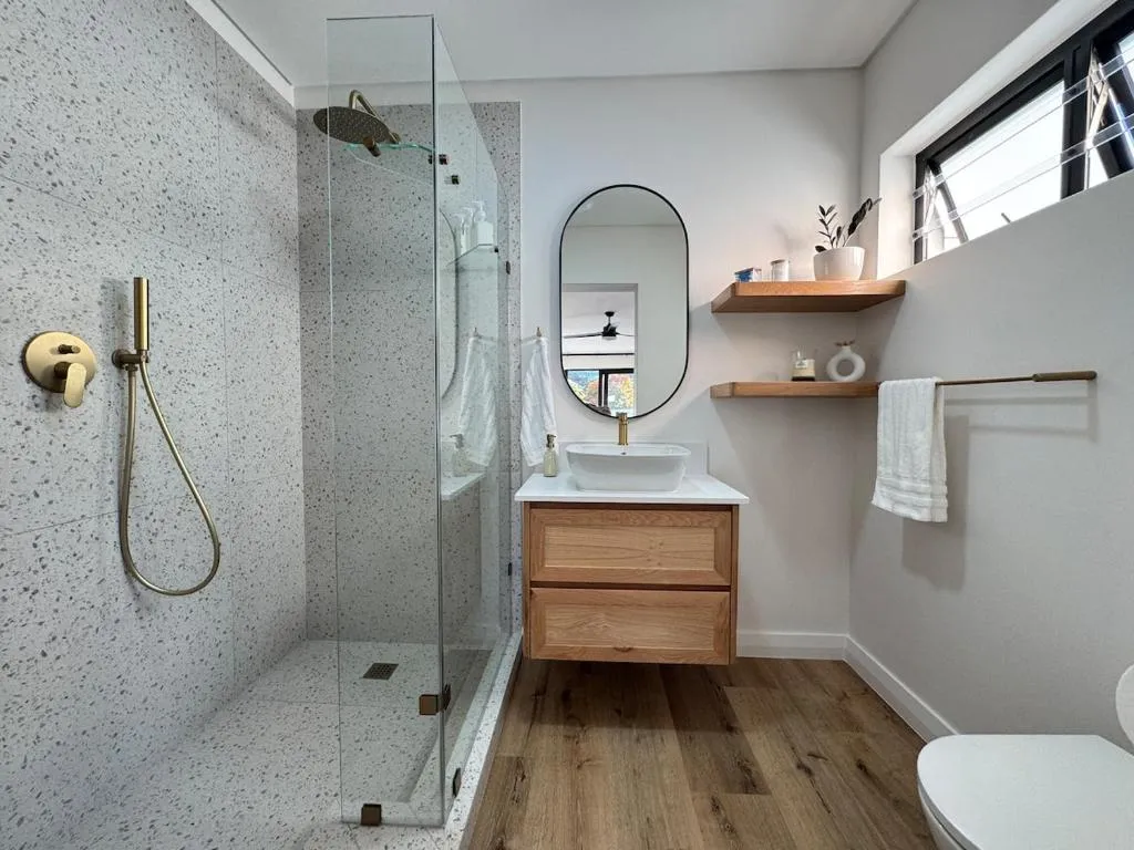 En-suite bathroom with a terrazzo-tiled shower, timber vanity and brass fittings