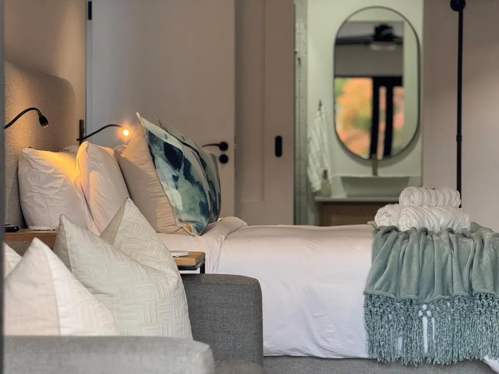 Close-up of bed linen and pillows with the en-suite bathroom visible beyond