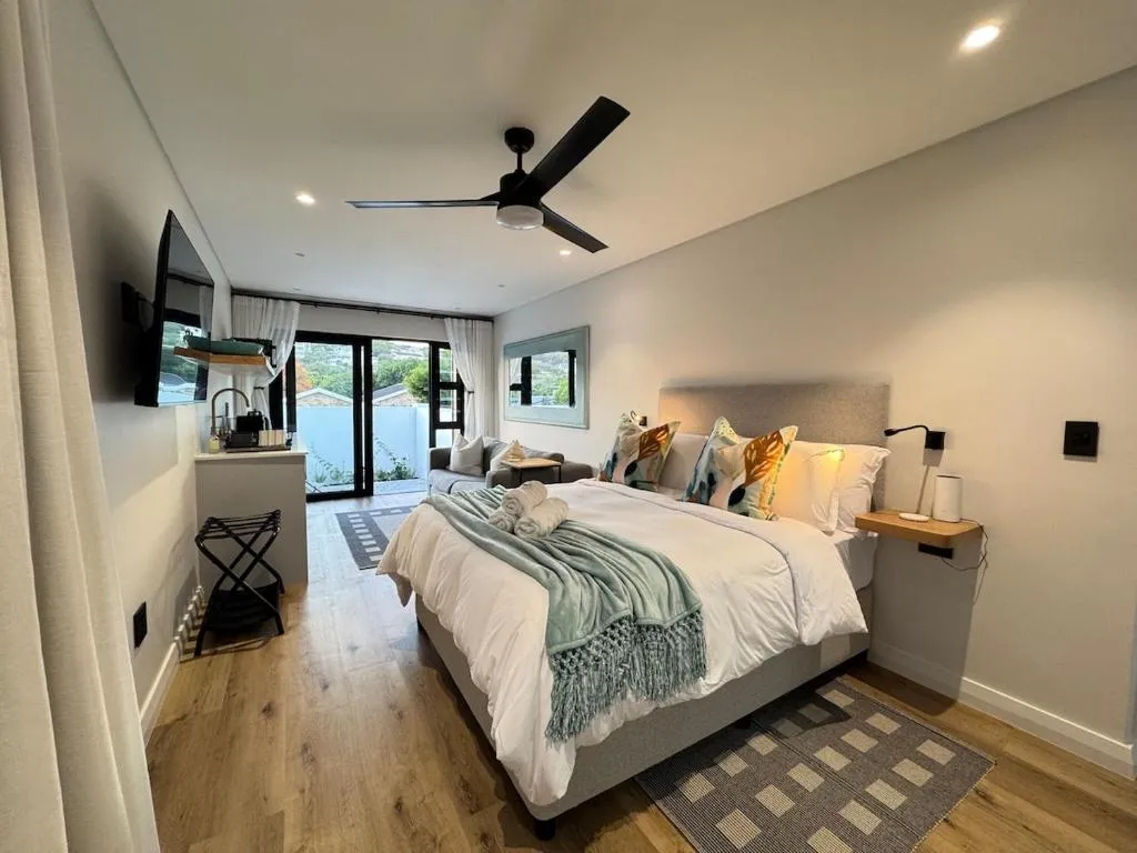 Studio bedroom with ceiling fan and glass sliding doors opening onto a private terrace