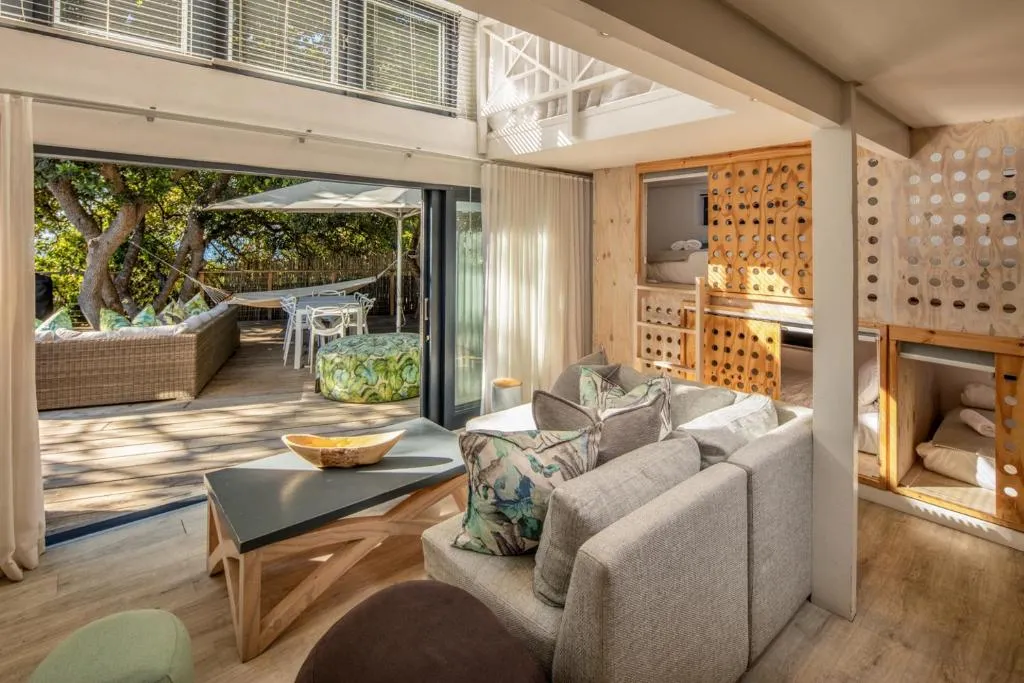 Living area with built-in bunk nooks opening onto a deck with a hammock and dining table