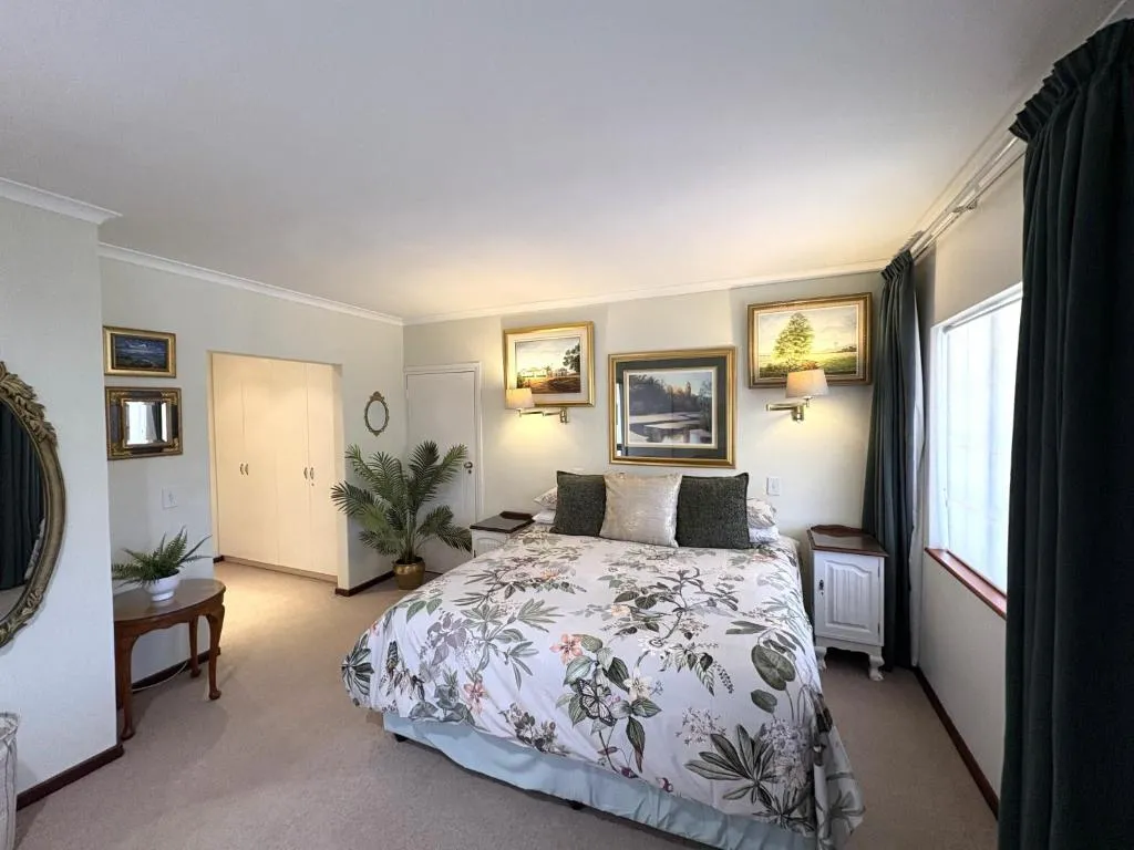 Bedroom with a floral duvet, built-in cupboards, and gallery-style framed artwork