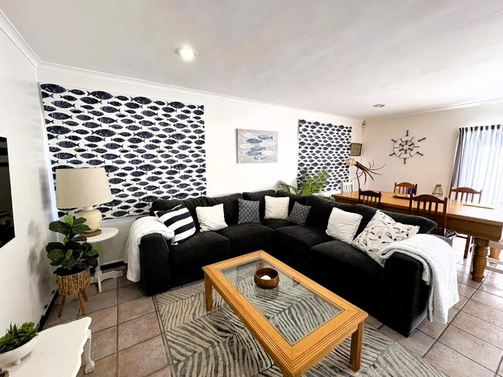 Second view of the lounge showing the corner sofa, coffee table, and rug on tiled floors